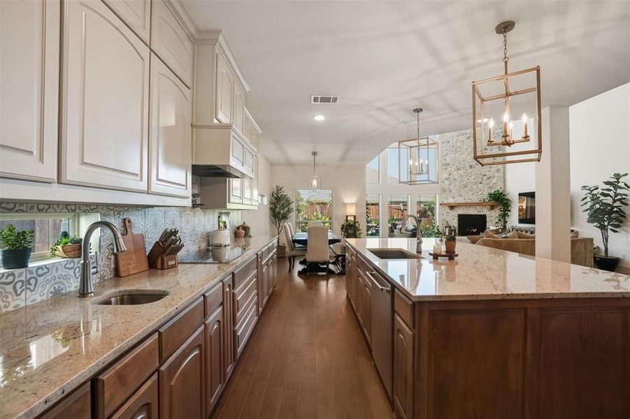 Kitchen featuring light stone counters, open floor plan, decorative light fixtures, dark wood-type flooring, and recessed lighting Kitchen featuring light stone counters, open floor plan, decorative light fixtures, dark wood-type flooring, and recessed lighting