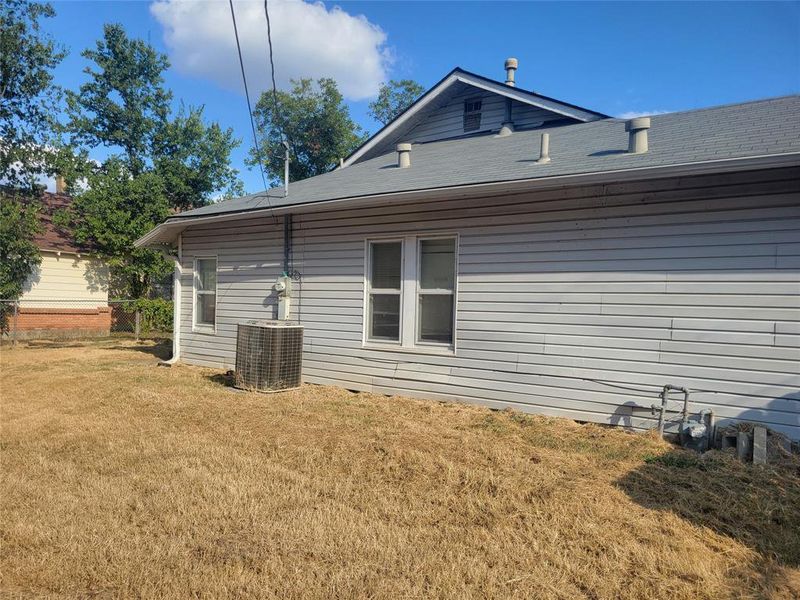 View of back of home with a lawn and central air condition unit