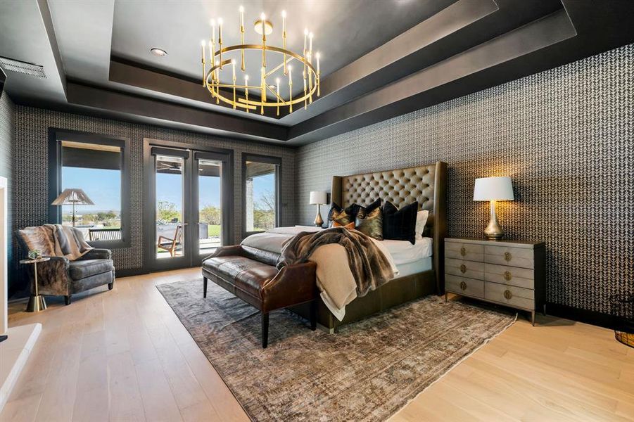 Bedroom with wallpapered walls, a tray ceiling, french doors, access to outside, and a chandelier Bedroom with wallpapered walls, a tray ceiling, french doors, access to outside, and a chandelier