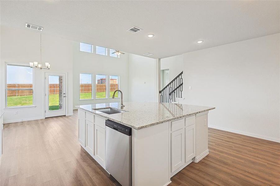 Kitchen featuring stainless steel dishwasher, white cabinets, a kitchen island with sink, and sink