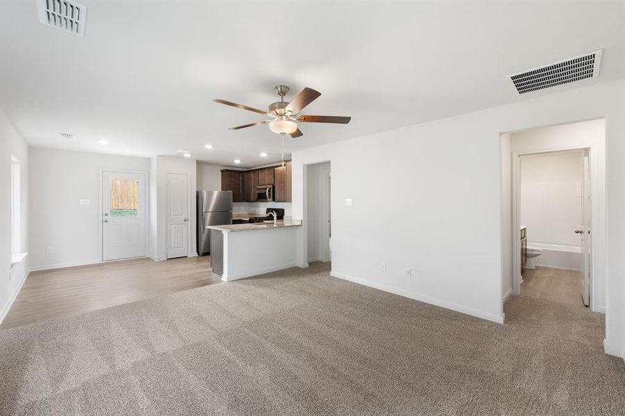 Living room with ceiling fan and light carpet