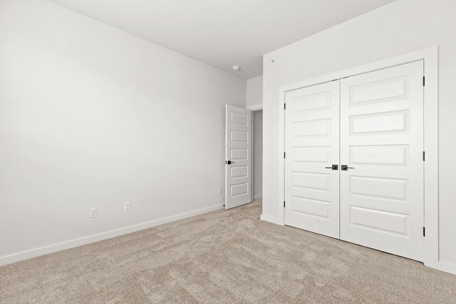 A well-lit bedroom with fresh carpet and clean white walls, ready for personalization. A well-lit bedroom with fresh carpet and clean white walls, ready for personalization.