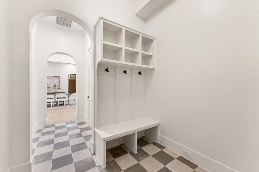 Gorgeous mosaic tile floors enhance the powder bath and mudroom with lockers. Gorgeous mosaic tile floors enhance the powder bath and mudroom with lockers.