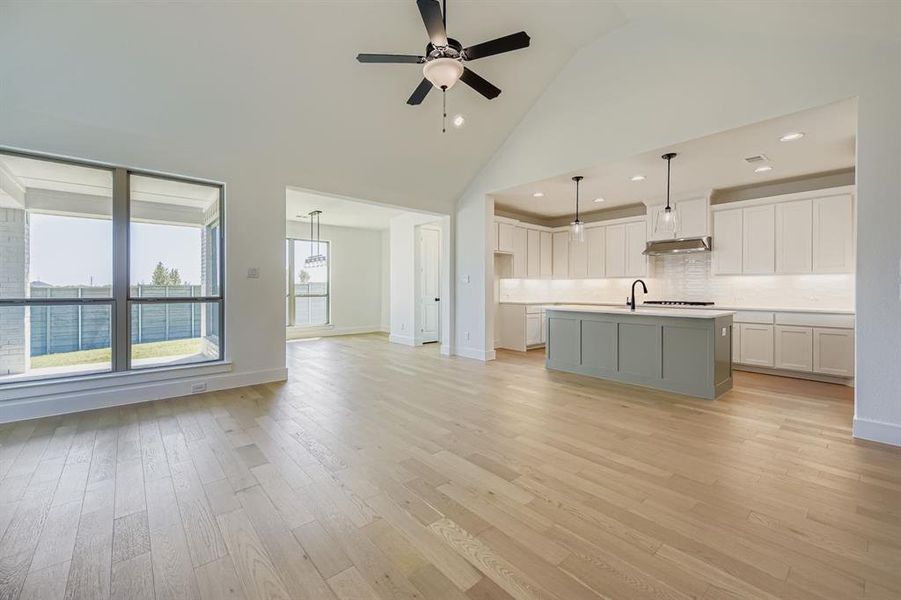 Unfurnished living room featuring high vaulted ceiling, light wood finished floors, ceiling fan, and recessed lighting Unfurnished living room featuring high vaulted ceiling, light wood finished floors, ceiling fan, and recessed lighting