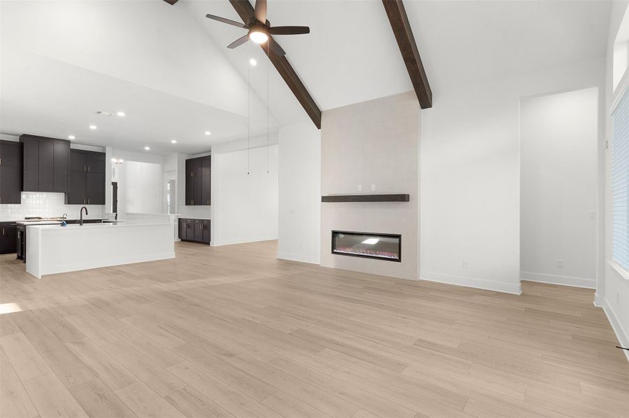 Unfurnished living room featuring high vaulted ceiling, light wood-style floors, a ceiling fan, recessed lighting, and beamed ceiling
