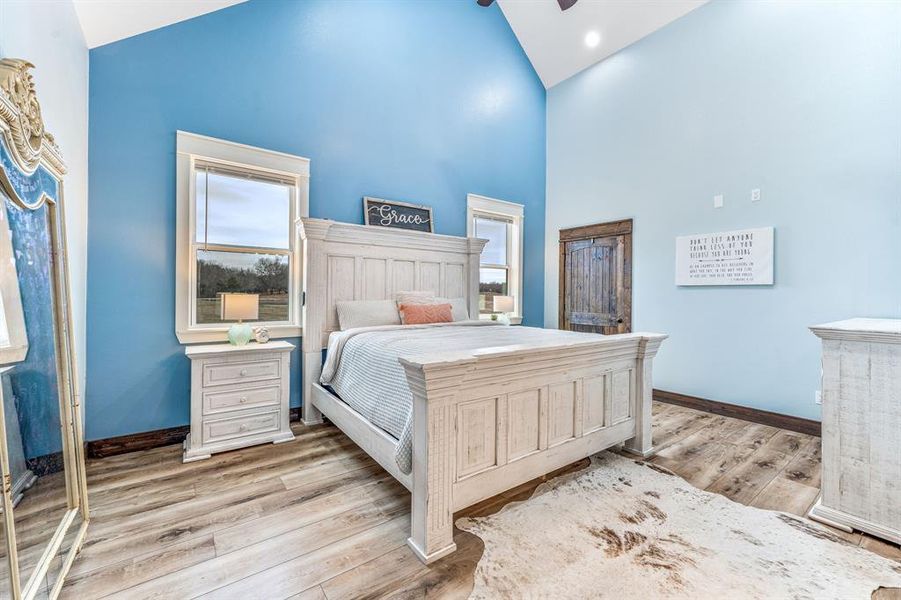 Bedroom with high vaulted ceiling and light wood finished floors