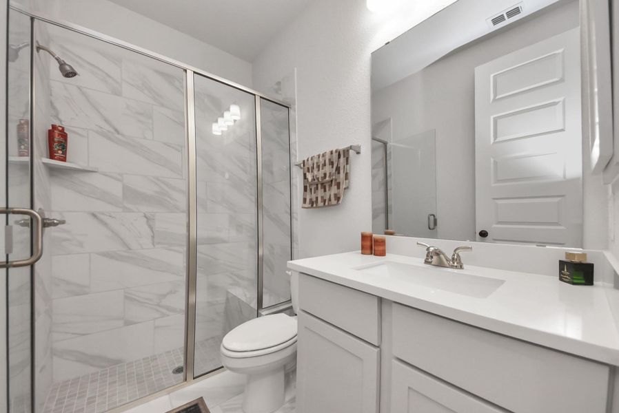 Modern bathroom featuring a glass-enclosed shower with marble tile, a sleek white vanity with ample counter space, and contemporary fixtures.
