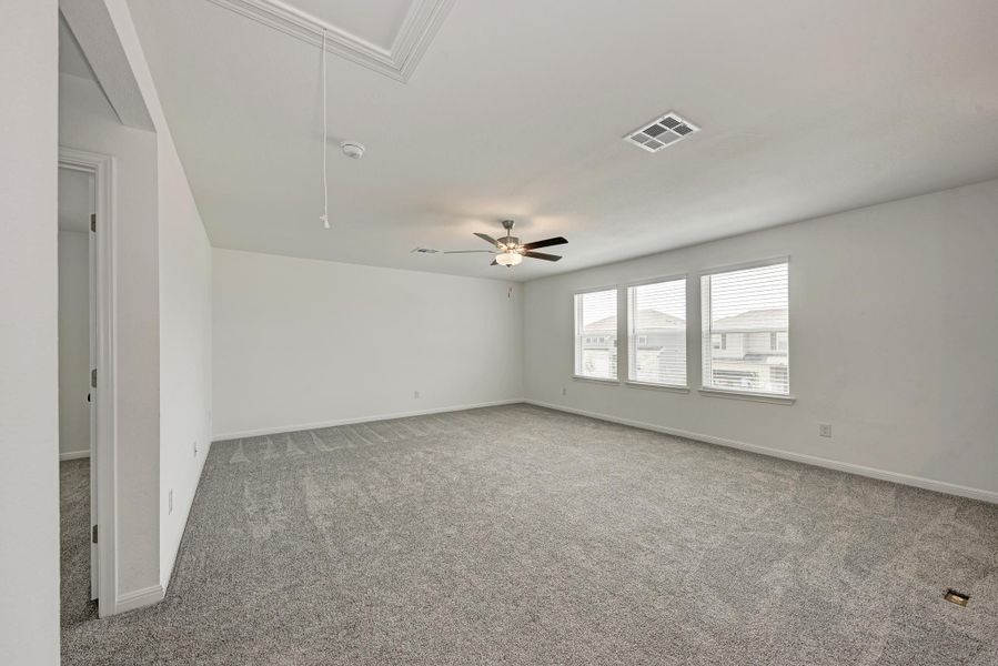 A spacious, airy living space features plush carpeting, well-lit windows, and a ceiling fan for comfort.