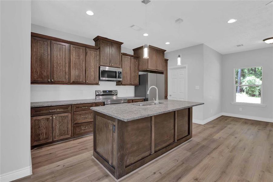 Pendant lighting makes it a little brighter over the island. Love these wooden cabinets!