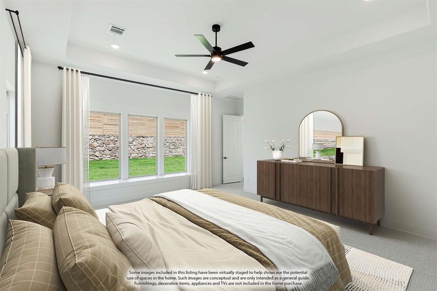 Bedroom with tray ceiling, ceiling fan, large windows, and wood dresser with mirror
