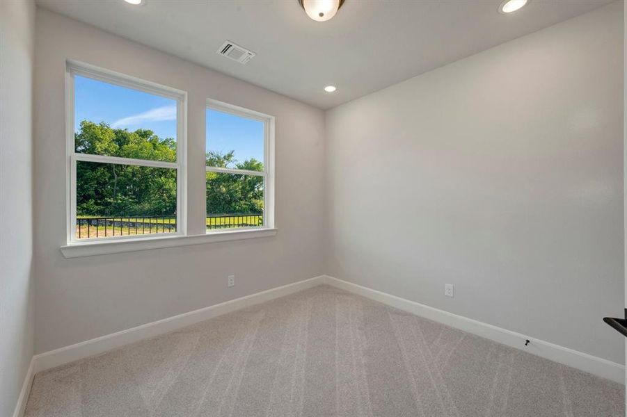 Bright room featuring two large windows with exterior foliage, neutral carpet flooring, recessed lighting, and a flush mount ceiling fixture