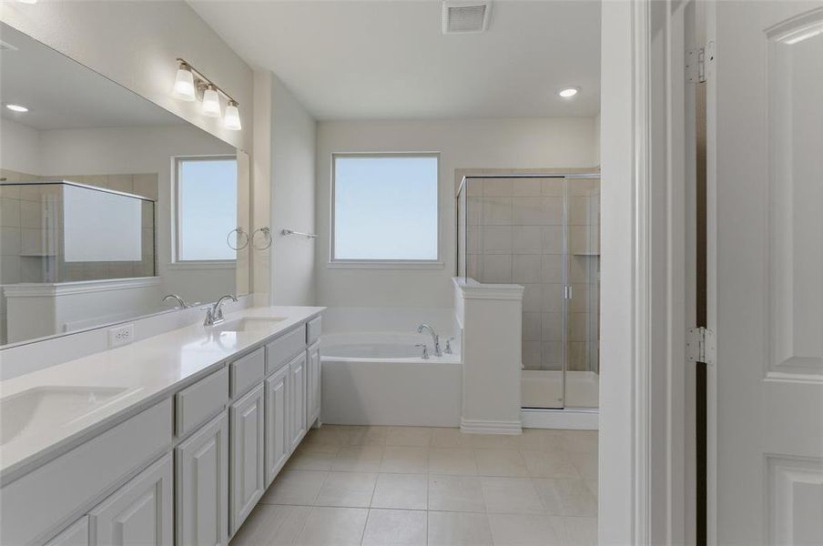 Spacious bathroom featuring a dual vanity with white cabinetry, light-toned countertops, and an oversized mirror Spacious bathroom featuring a dual vanity with white cabinetry, light-toned countertops, and an oversized mirror