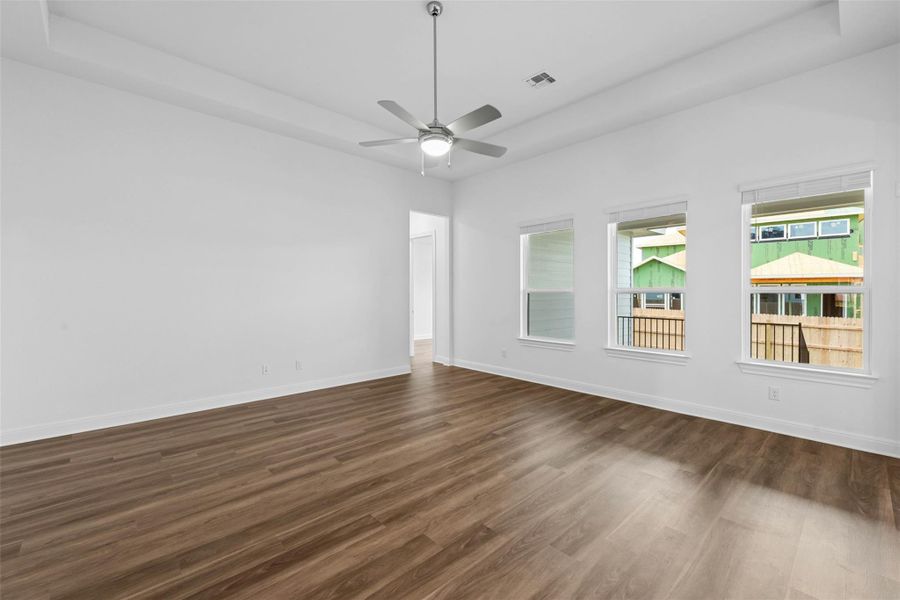 A naturally illuminated living space boasts pristine walls and durable wood flooring, awaiting personal touches.