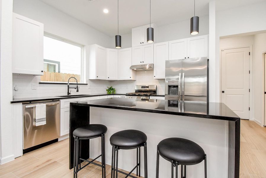 Elegant kitchen featuring a spacious island bar is accented with dimmable pendant lighting.