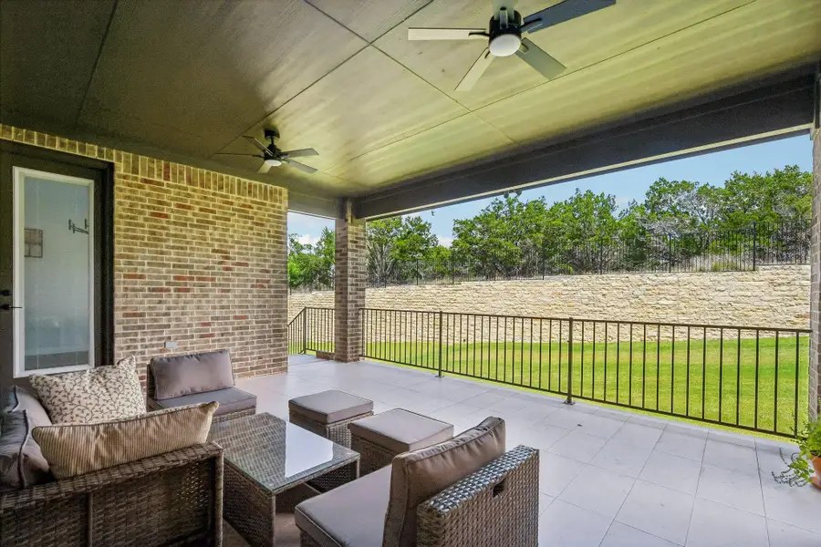 An inviting covered patio offers ample space for entertaining with ceiling fans for comfort and a lush backyard view.