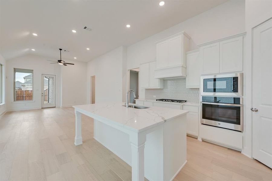 Kitchen featuring stainless steel appliances, decorative backsplash, white cabinetry, recessed lighting, and light wood-type flooring Kitchen featuring stainless steel appliances, decorative backsplash, white cabinetry, recessed lighting, and light wood-type flooring