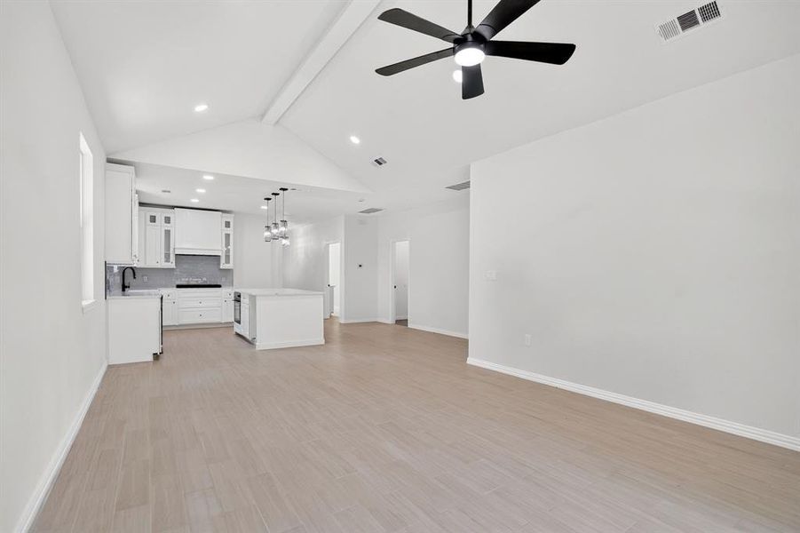 Open-concept living space featuring wood-finish flooring and a vaulted ceiling