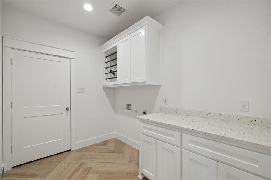 Laundry area with light parquet floors, cabinets, electric dryer hookup, and washer hookup