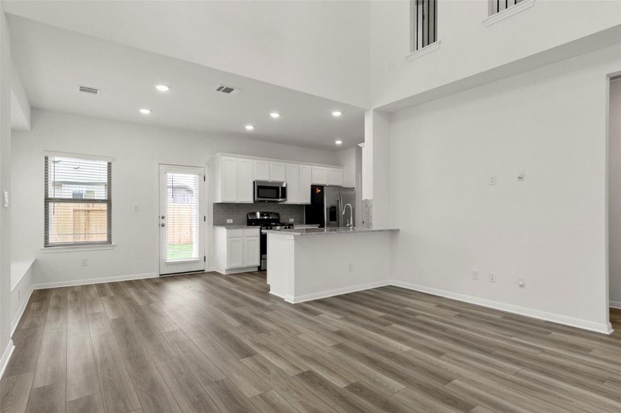 Kitchen with recessed lighting, white cabinetry, wood finished floors, open floor plan, and appliances with stainless steel finishes