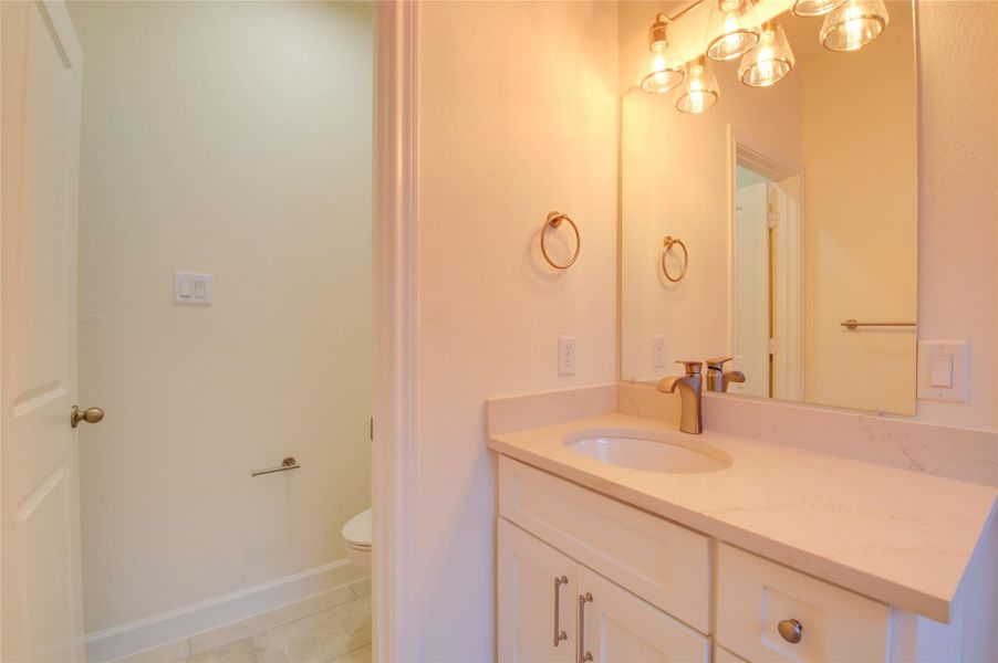 Sleek secondary bath with quartz vanity, goldfaucet and hardware, and designer glass lighting.Private water closet and neutral tile floors keep thespace bright and functional. Sleek secondary bath with quartz vanity, goldfaucet and hardware, and designer glass lighting.Private water closet and neutral tile floors keep thespace bright and functional.