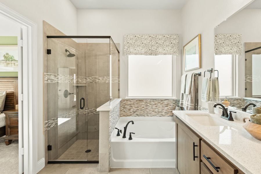 Master bathroom with glass walk-in shower, soaking tub, and double vanity with quartz countertop