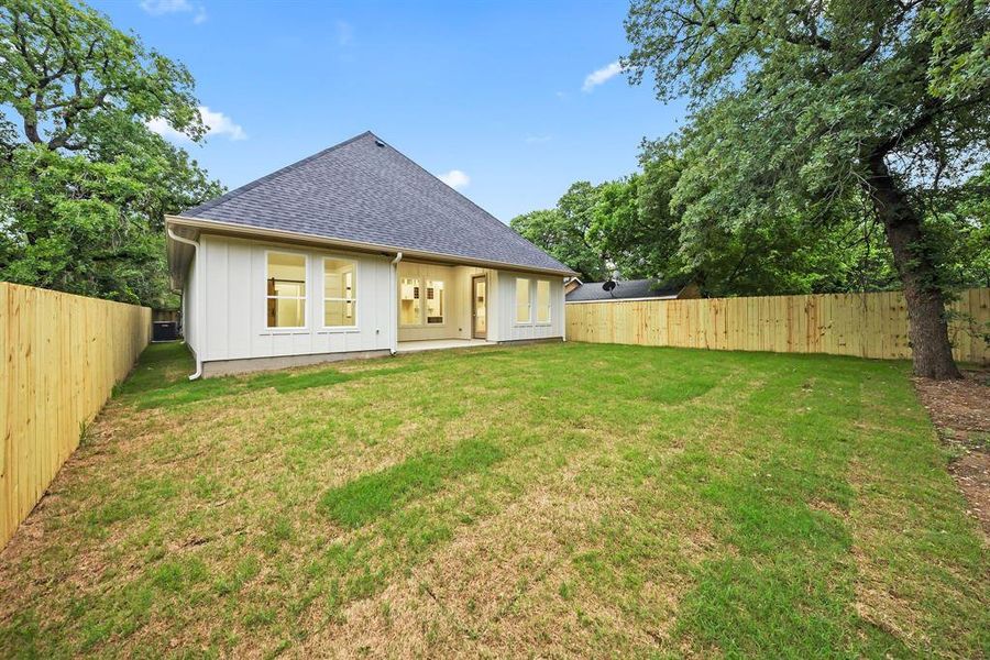 Expansive backyard featuring a new privacy fence, mature trees, a manicured lawn, and a rear patio