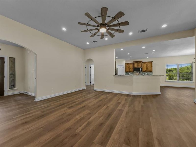 Unfurnished living room with arched walkways, a ceiling fan, recessed lighting, and dark wood finished floors Unfurnished living room with arched walkways, a ceiling fan, recessed lighting, and dark wood finished floors