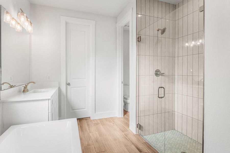 Luxurious bathroom with wood-look tile flooring and a spacious glass-enclosed shower. Luxurious bathroom with wood-look tile flooring and a spacious glass-enclosed shower.