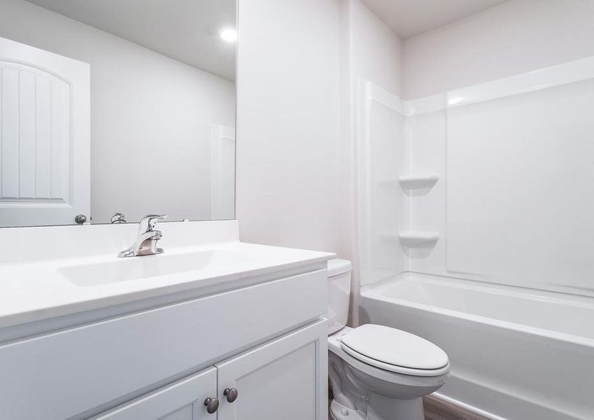 Secondary bathroom with white cabinets.