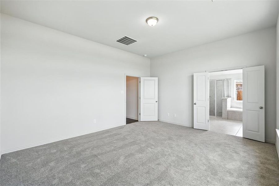 Unfurnished bedroom featuring carpet flooring, ensuite bath, and tile patterned flooring Unfurnished bedroom featuring carpet flooring, ensuite bath, and tile patterned flooring