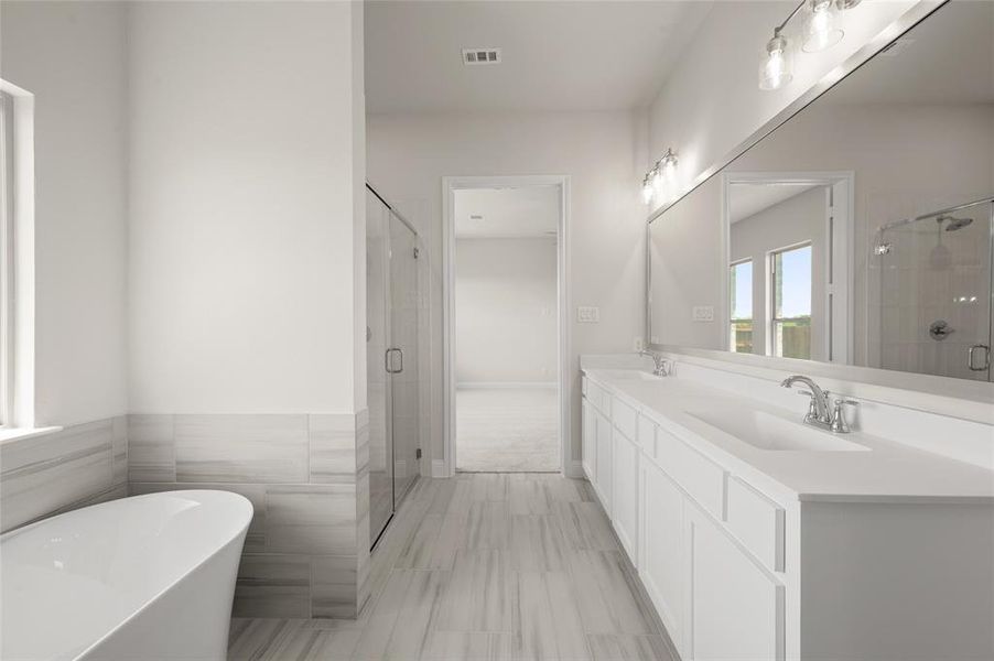 Full bath featuring a freestanding bath, a shower stall, and double vanity