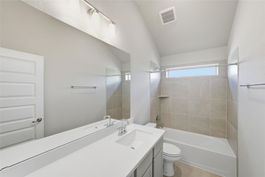 Full bath featuring shower / bathtub combination, vanity, vaulted ceiling, and light tile patterned floors