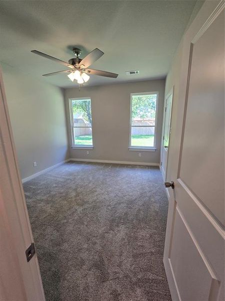 Carpeted spare room featuring a healthy amount of sunlight and ceiling fan