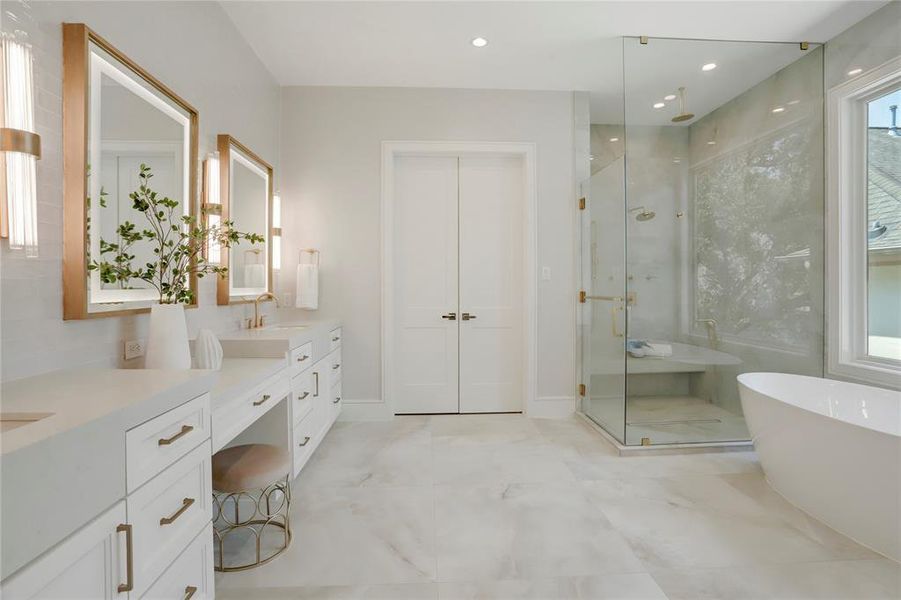 The gorgeous Primary Bathroom features beautiful porcelain tile flooring, brass hardware and plumbing fixtures, a free-standing soaking tub and a large walk-in shower with frameless glass, porcelain tilesurround, bench, rain shower head, wall shower head, handheld shower head and linear drain.