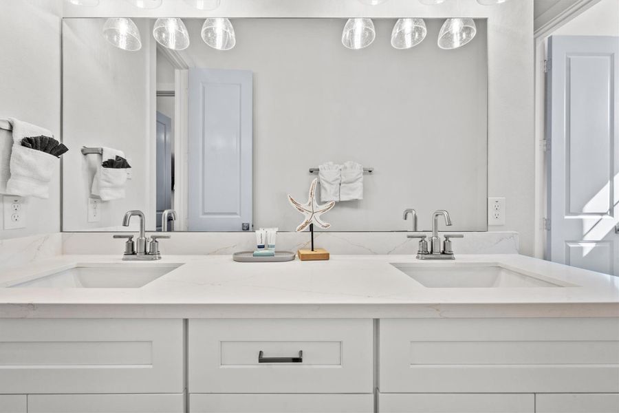 Guest bedroom one offers direct access to a Hollywood-style bath, featuring dual sinks and a quartz vanity.