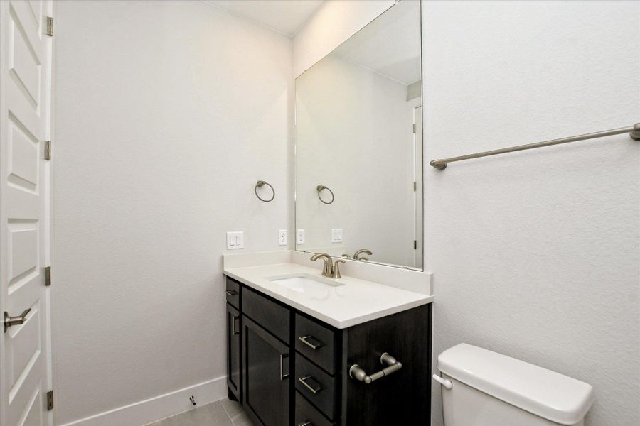 Bathroom featuring baseboards, toilet, tile patterned flooring, and vanity