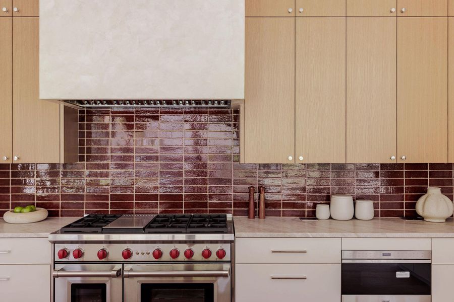 Kitchen featuring appliances with stainless steel finishes, light countertops, decorative backsplash, and wall chimney exhaust hood Kitchen featuring appliances with stainless steel finishes, light countertops, decorative backsplash, and wall chimney exhaust hood