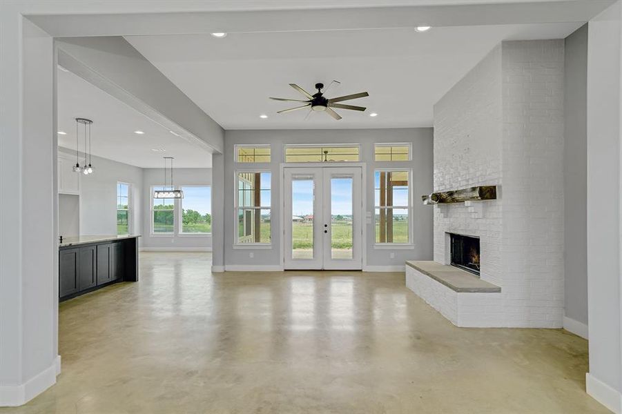 Unfurnished living room featuring concrete floors, baseboards, a fireplace, recessed lighting, and ceiling fan