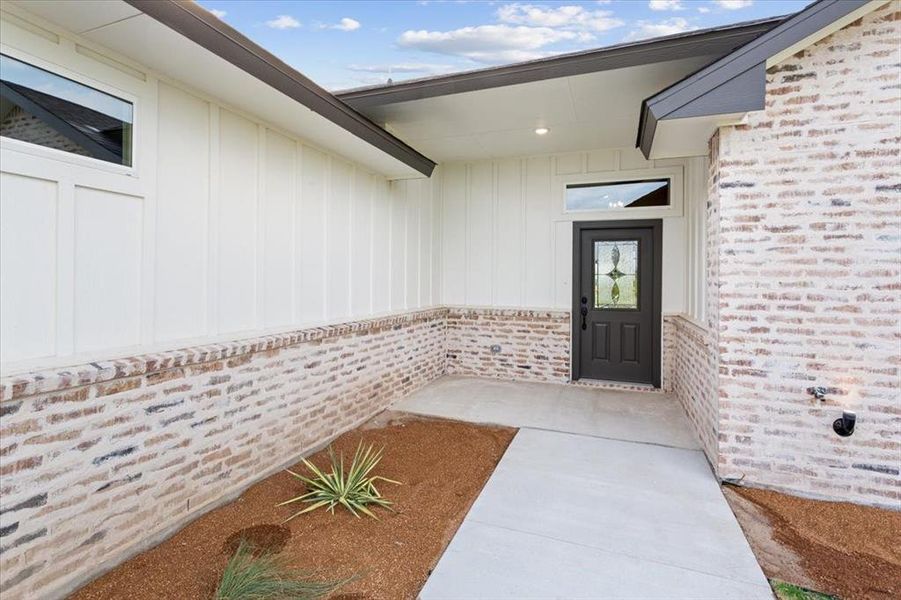 Entrance to property featuring brick siding and board and batten siding