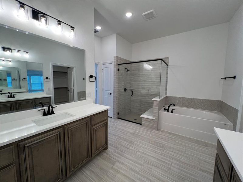 Master bathroom featuring two vanities, a shower stall, a garden tub, ceramic flooring, and linen closet Master bathroom featuring two vanities, a shower stall, a garden tub, ceramic flooring, and linen closet