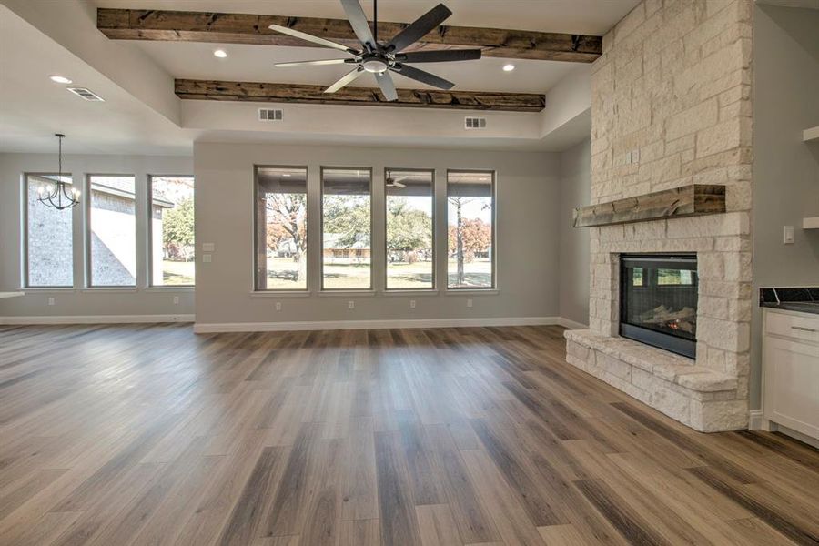 Unfurnished living room featuring a stone fireplace, plenty of natural light, and hardwood / wood-style flooring