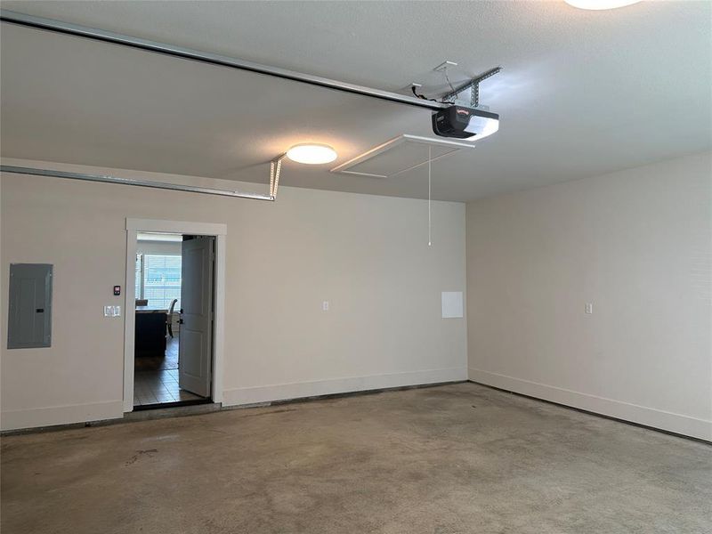 Spacious garage featuring a concrete floor, light-toned walls, overhead lighting, an automatic garage door opener, and interior access
