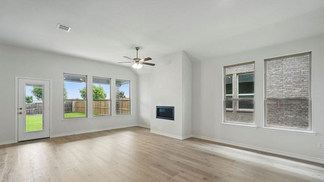 Unfurnished living room with a glass covered fireplace, a ceiling fan, and light wood-style flooring