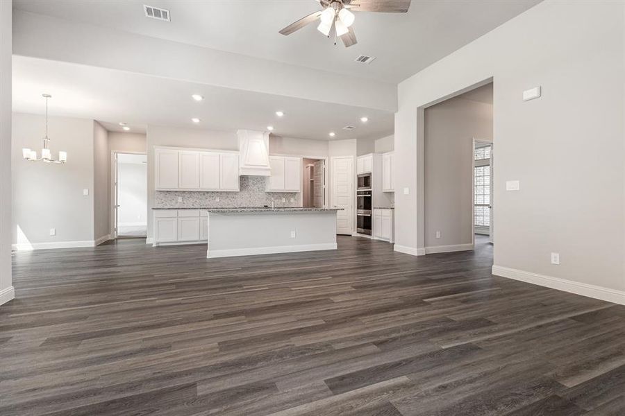 Unfurnished living room featuring dark wood-style floors, recessed lighting, a chandelier, and a ceiling fan Unfurnished living room featuring dark wood-style floors, recessed lighting, a chandelier, and a ceiling fan