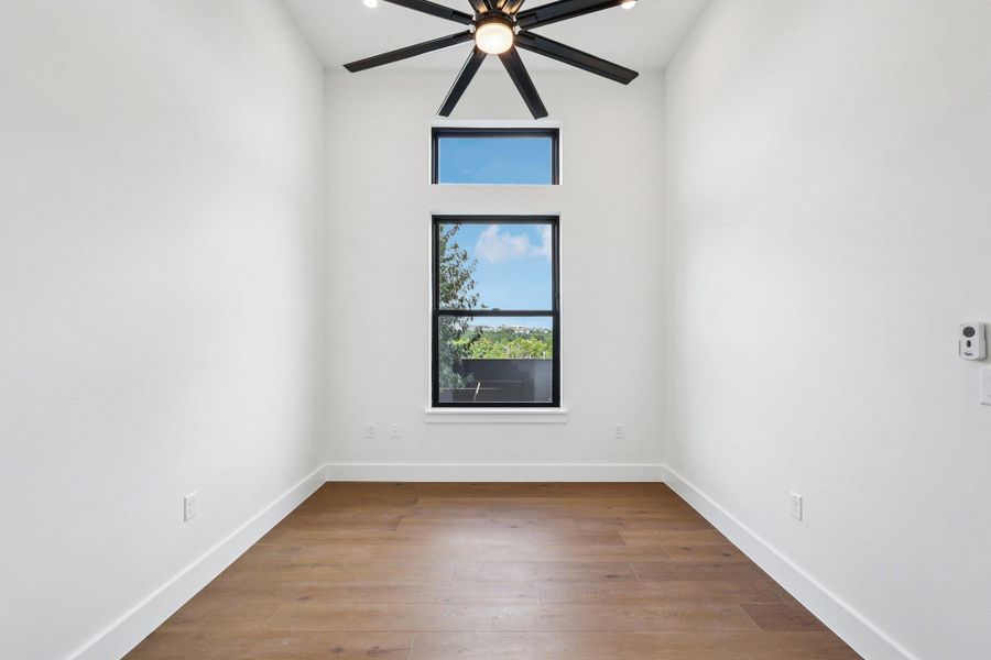 Study with light wood finished floors, French doors and a ceiling fan
