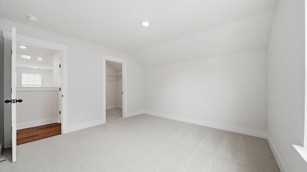 First-rate secondary bedroom with a spacious walk-in closet and elegant carpeted flooring located at Iris Meadows