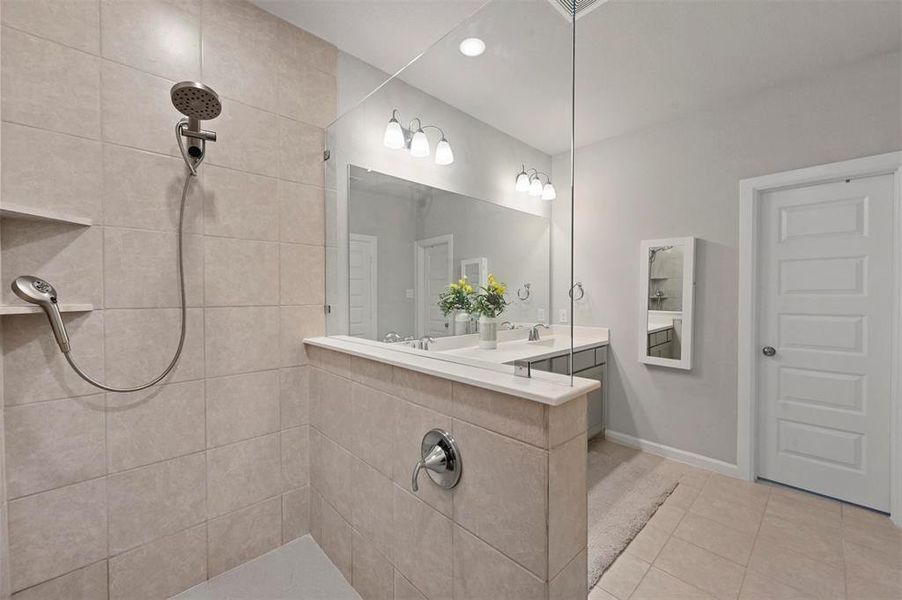 Bathroom featuring tiled shower, tile patterned floors, and double vanity Bathroom featuring tiled shower, tile patterned floors, and double vanity
