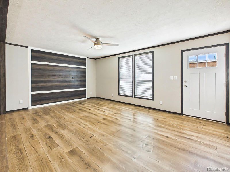 Living Area – Open living area with wide-plank flooring, ceiling fan, and a flexible layout that connects seamlessly to adjacent spaces.