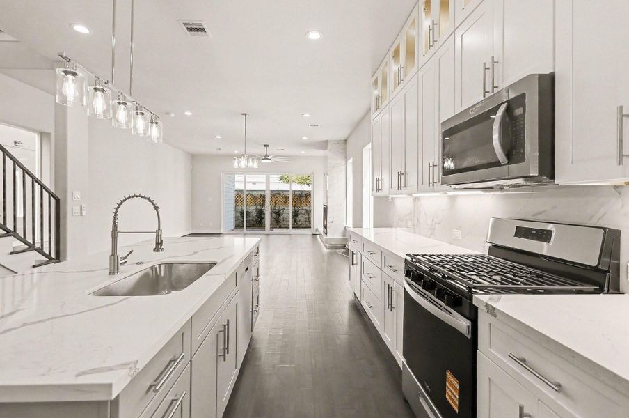 Stylish kitchen with stainless steel appliances, designer backsplash, and abundant storage.