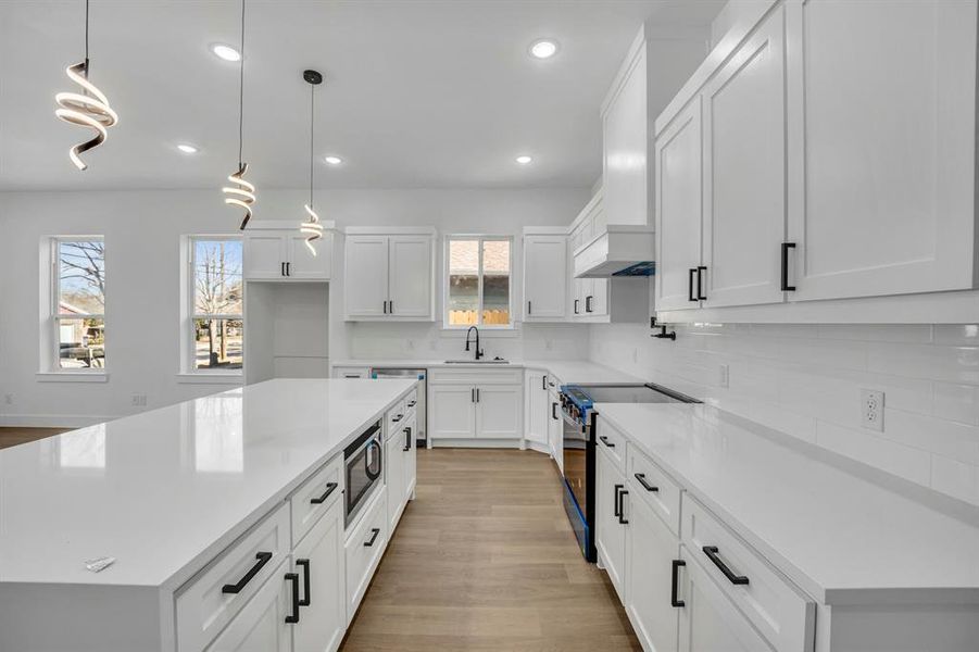 Kitchen featuring white cabinetry, pendant lighting, range with electric cooktop, and a center island